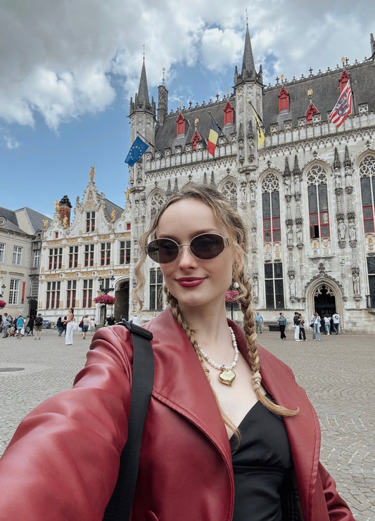 Woman taking a selfie in front of a historic building with flags in the background