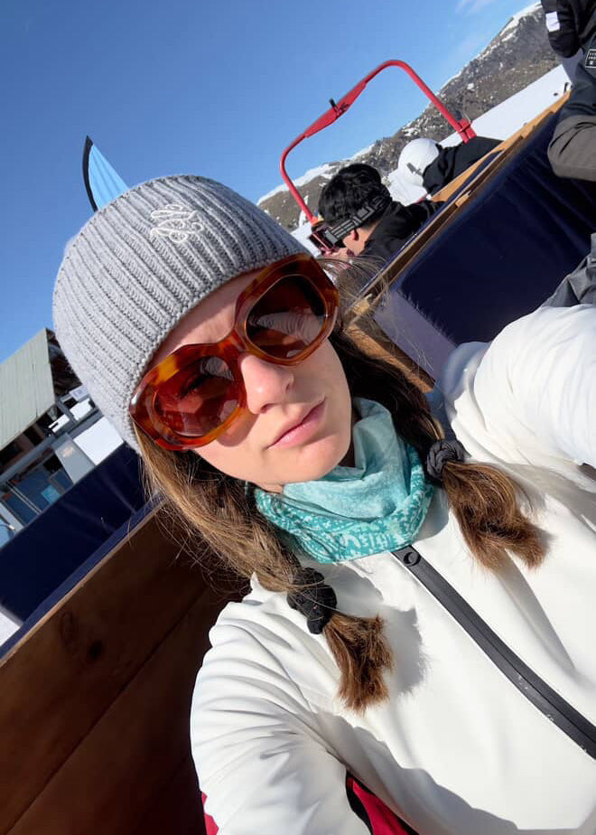 Person wearing sunglasses and a beanie in a mountainous area