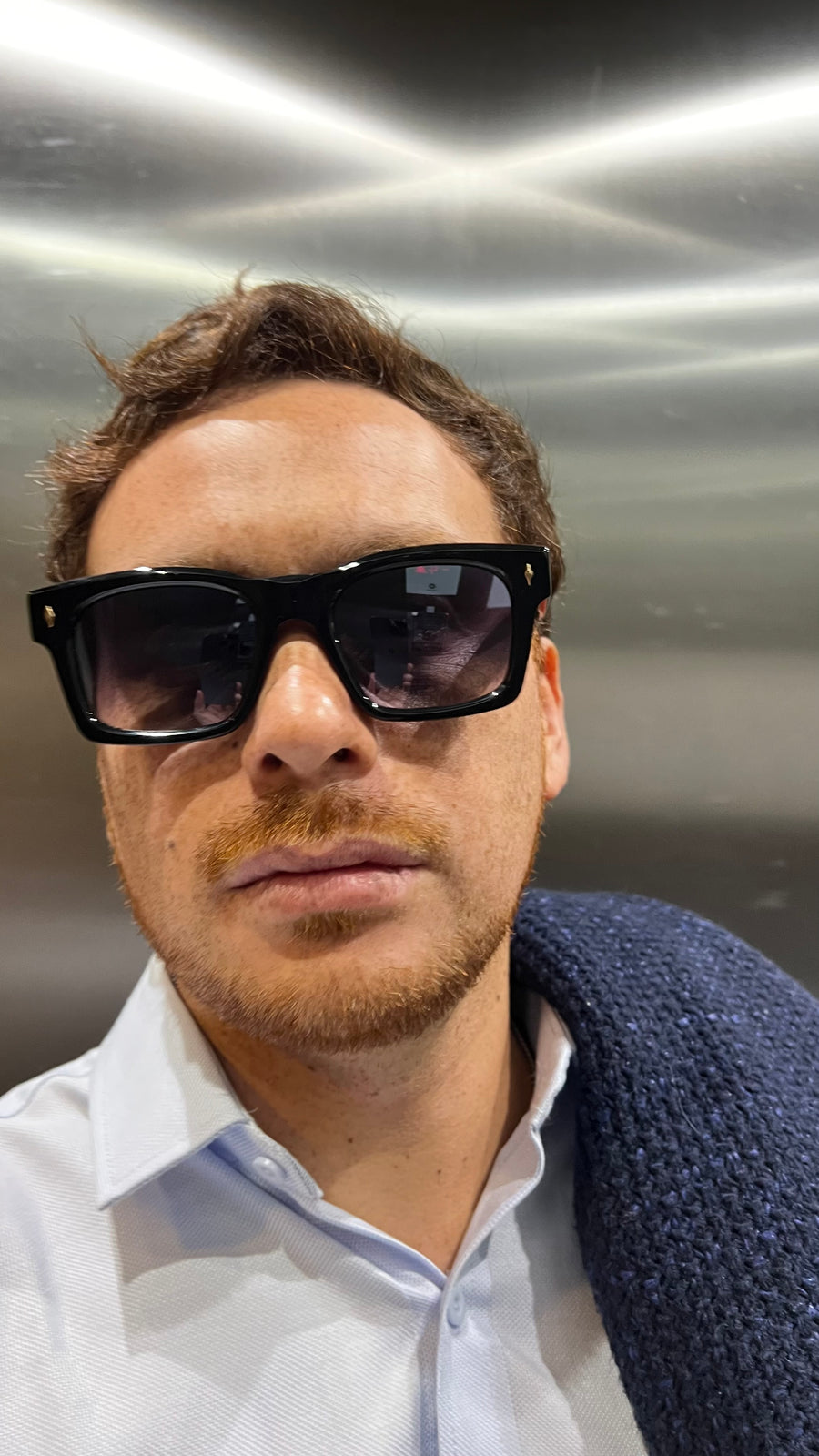 Man wearing sunglasses in an elevator setting