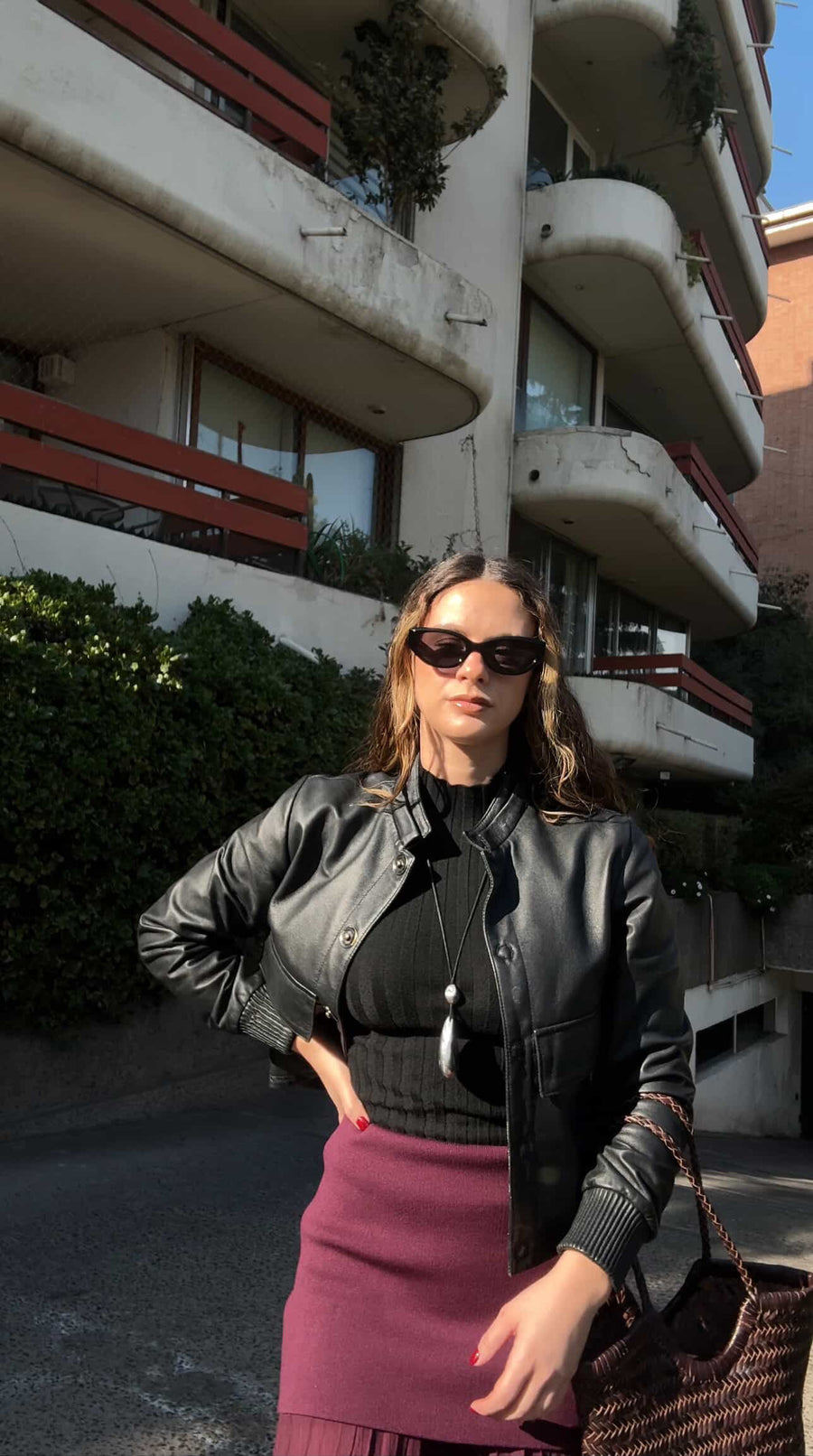 Woman wearing sunglasses and a black leather jacket in front of a building