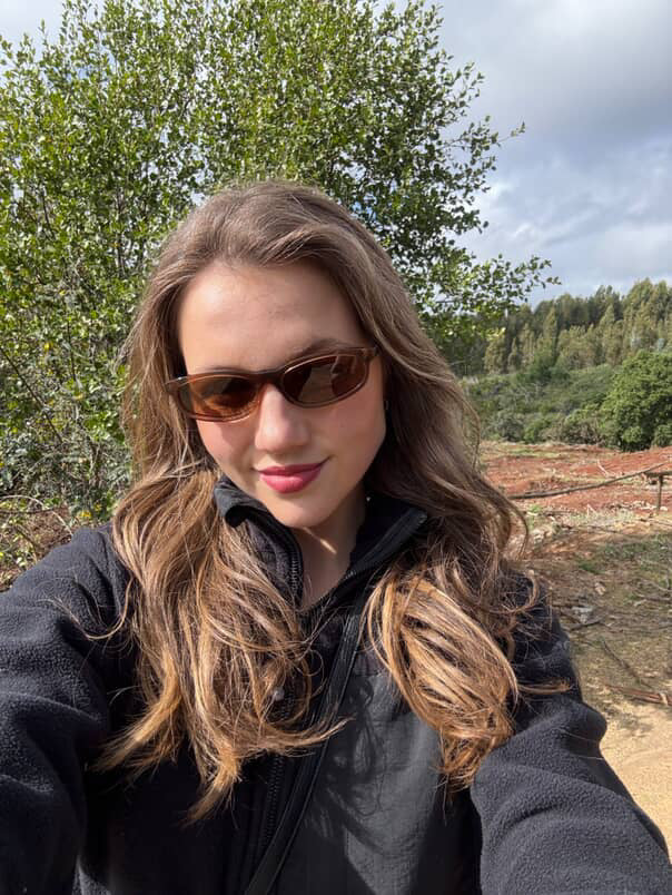 Woman wearing sunglasses outdoors with trees in the background