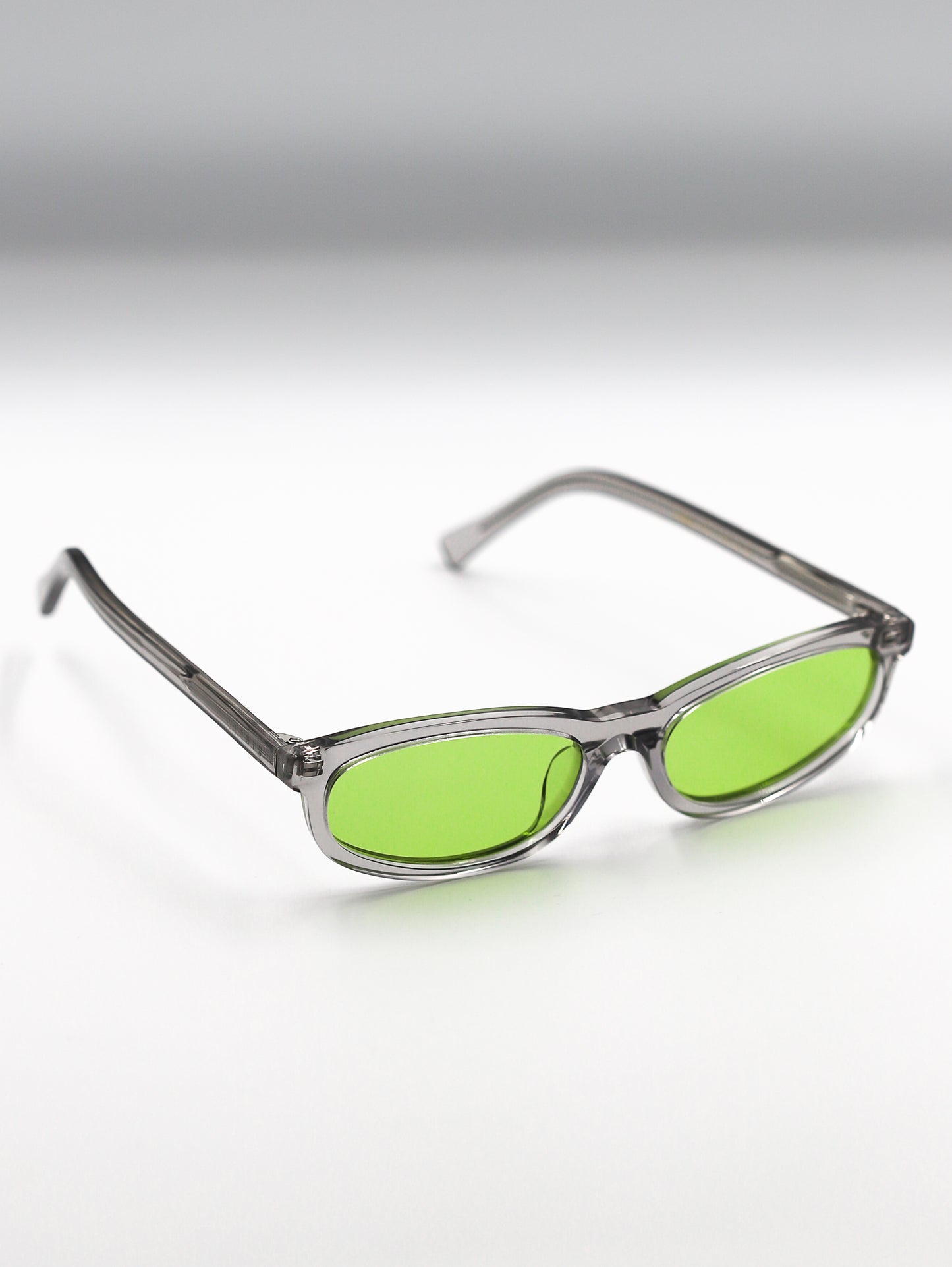 Sunglasses with green lenses and clear frames on a gradient background