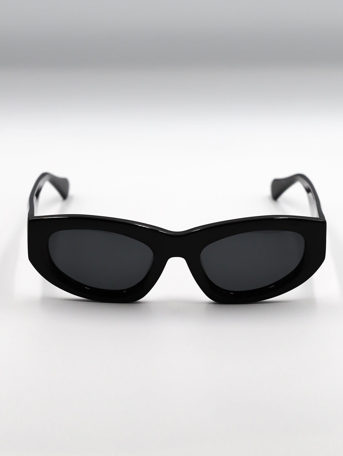 Black sunglasses with dark lenses on a light gray background