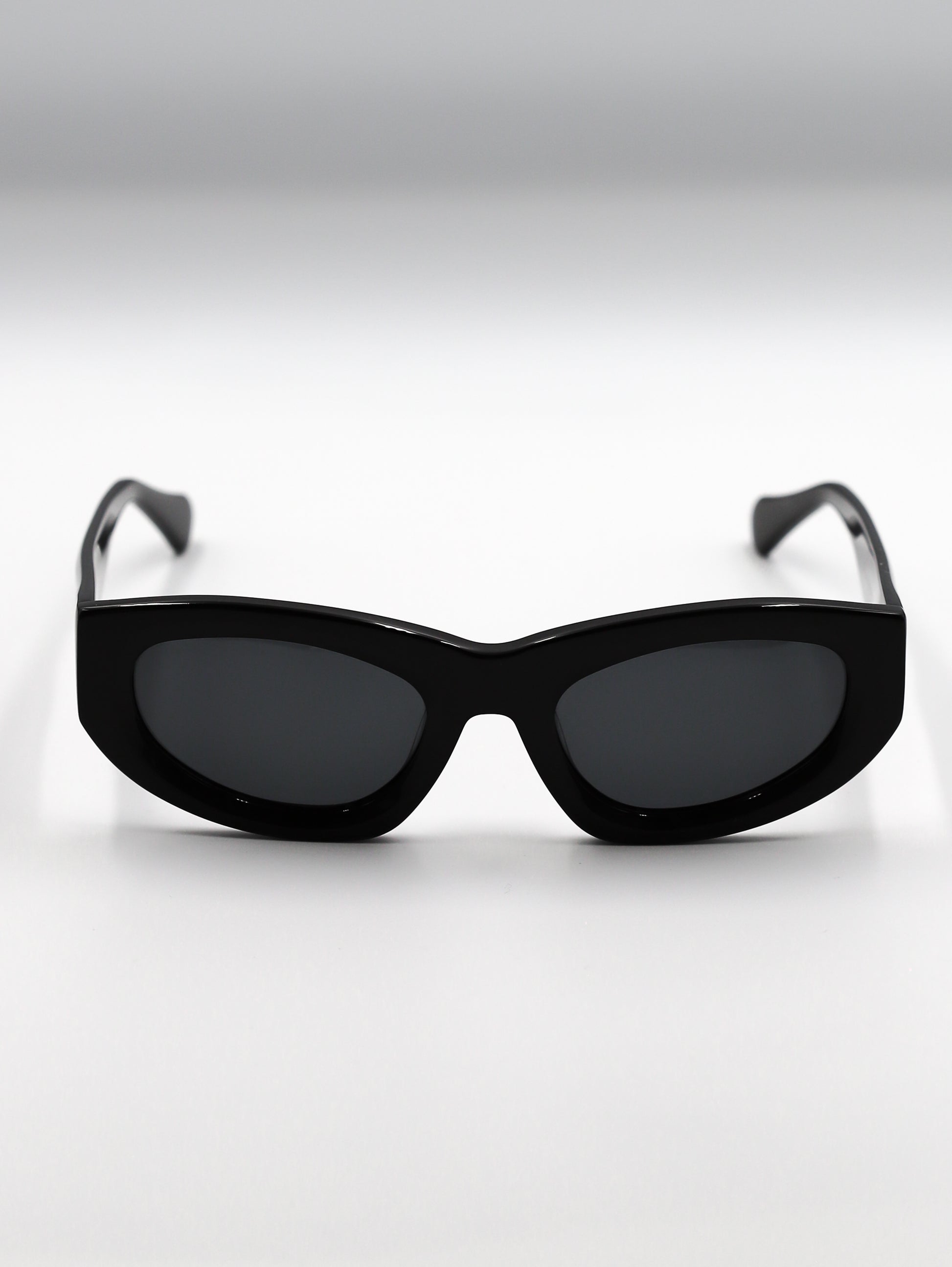 Black sunglasses with dark lenses on a light gray background