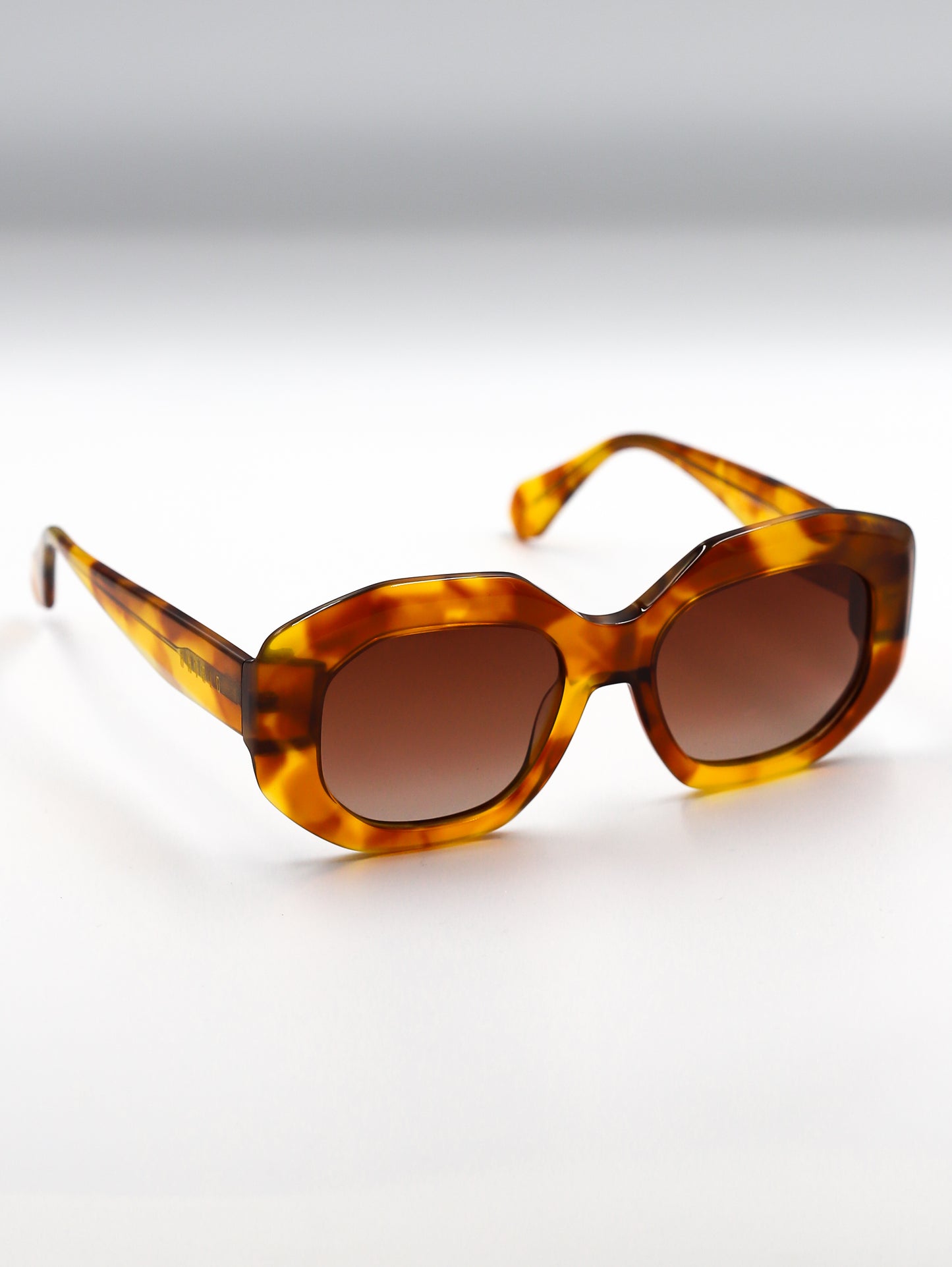 Tortoiseshell sunglasses with brown lenses on a light gray background