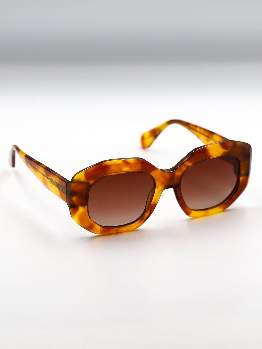 Tortoiseshell sunglasses with brown lenses on a light gray background