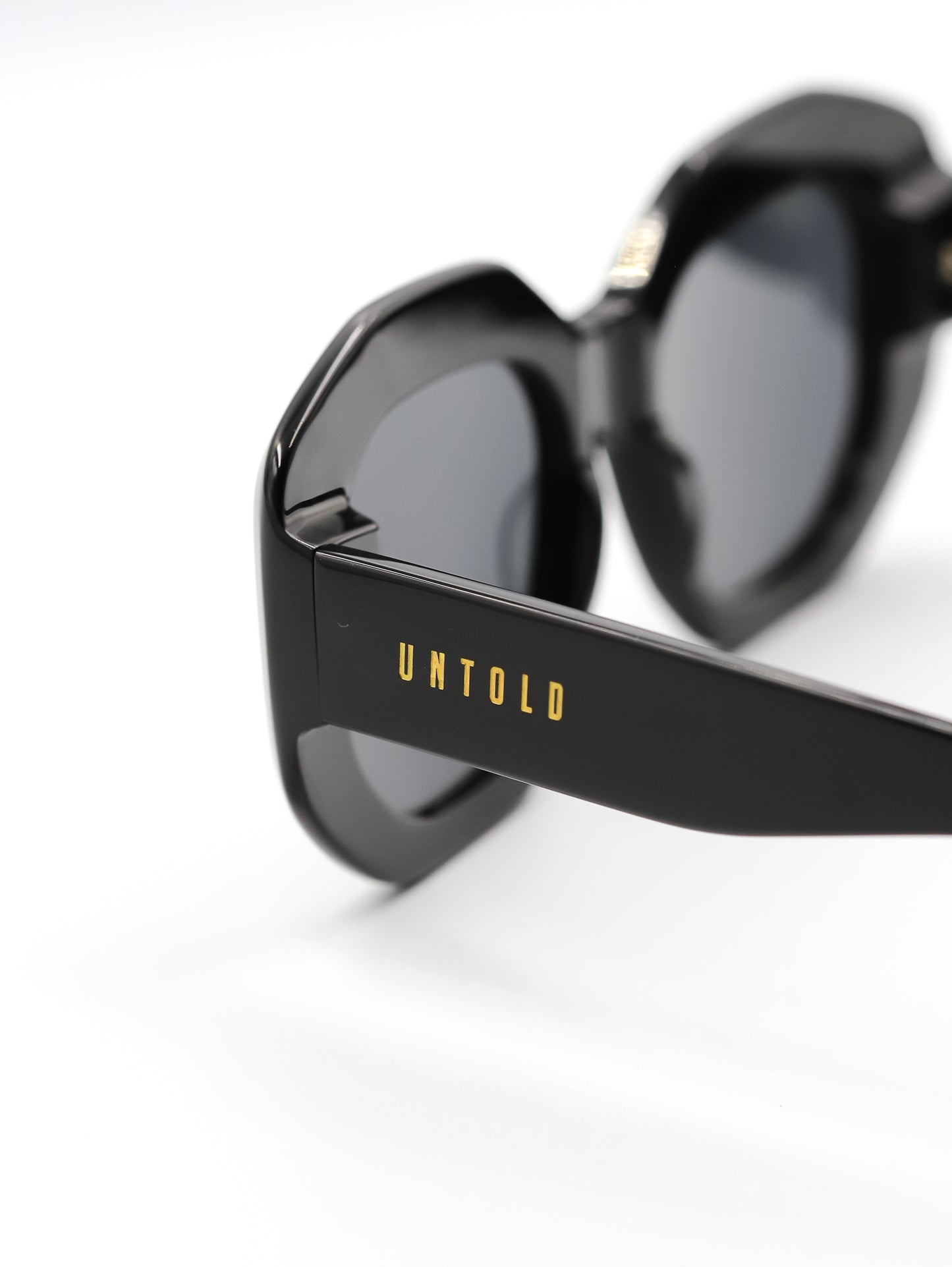 Black sunglasses with 'Untold' branding on a white background