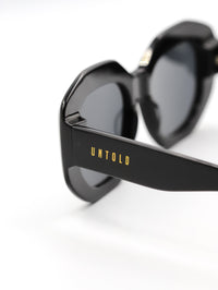 Thumbnail for Black sunglasses with 'Untold' branding on a white background