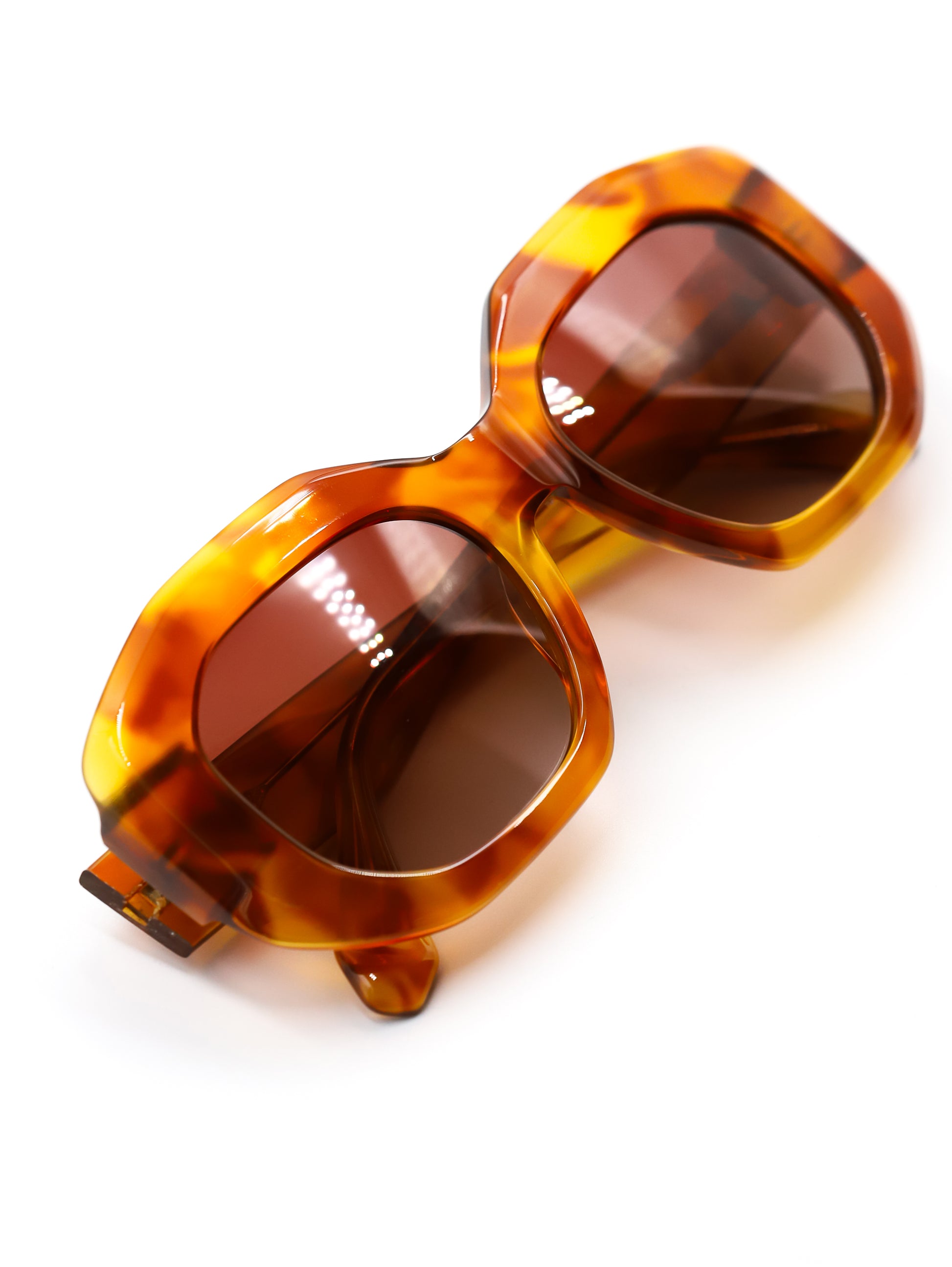 Tortoiseshell sunglasses with brown lenses on a white background