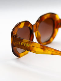 Thumbnail for Tortoiseshell sunglasses with a brand name on a white background