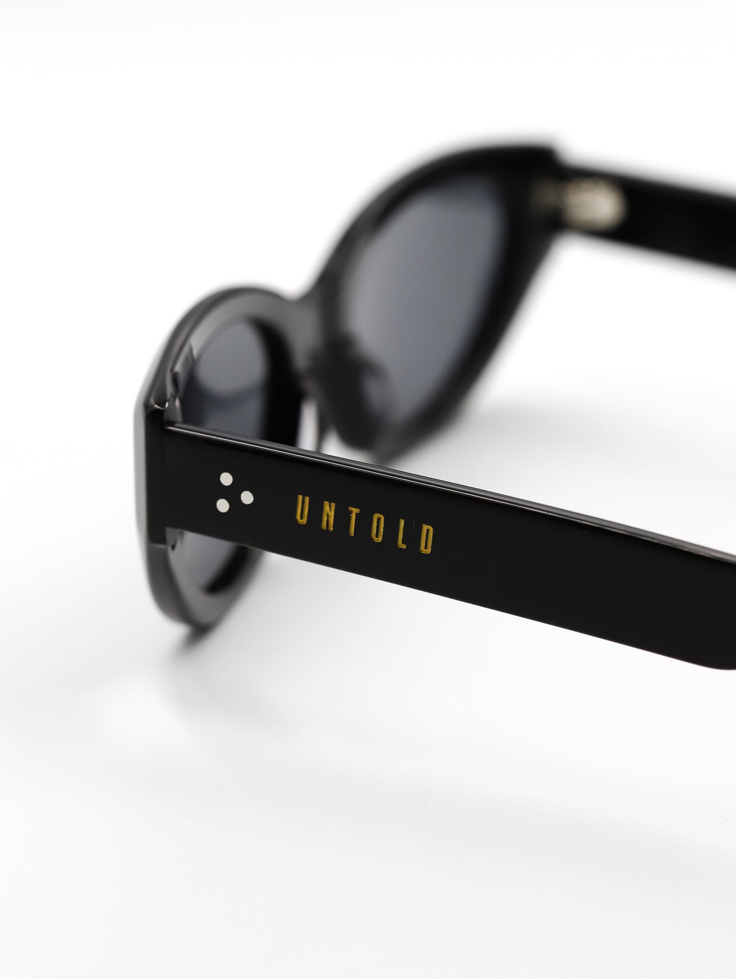 Black sunglasses with 'Untold' branding on a white background