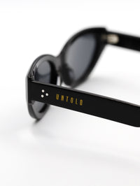 Thumbnail for Black sunglasses with 'Untold' branding on a white background