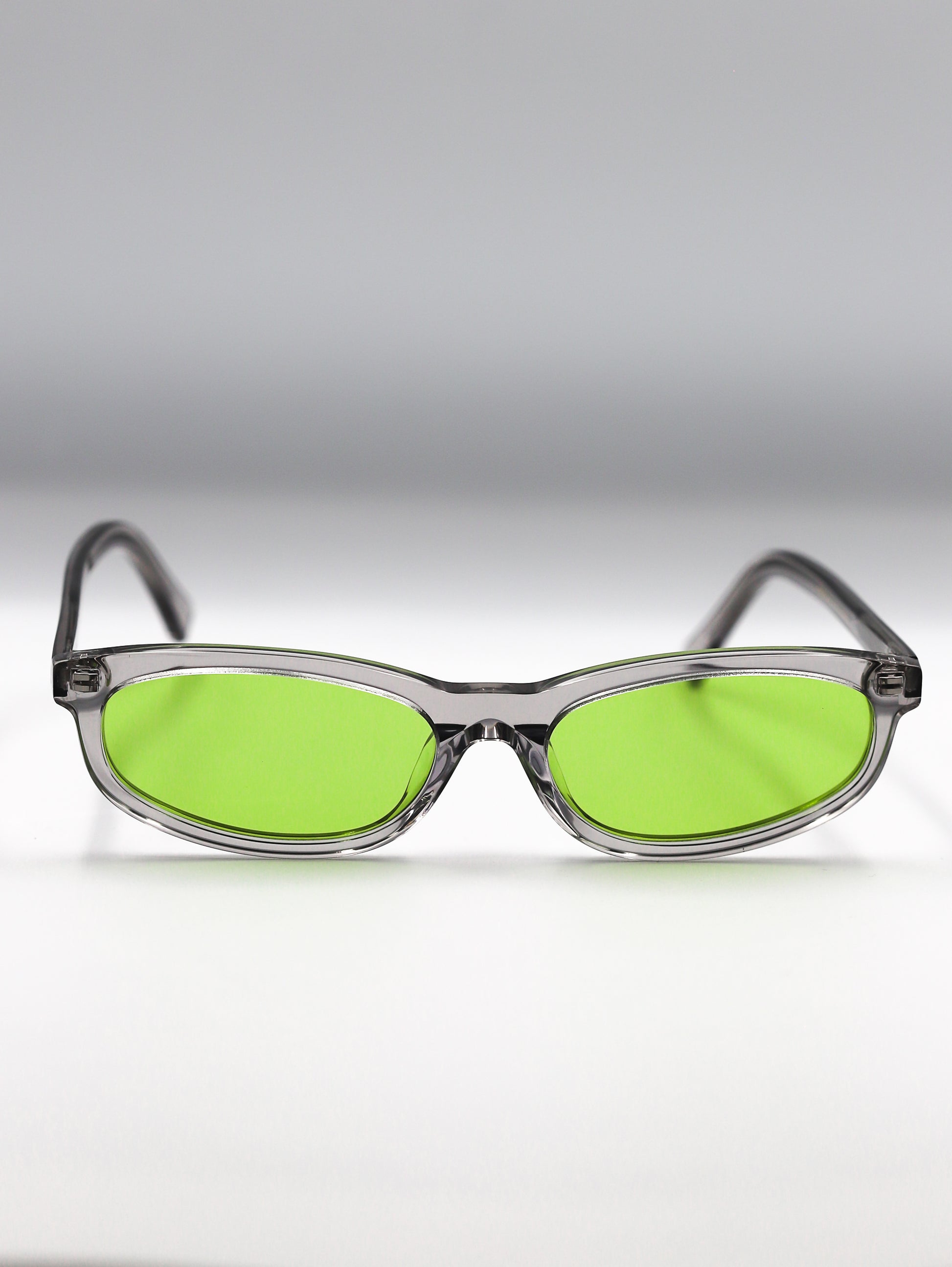 Sunglasses with green lenses and clear frames on a gradient gray background