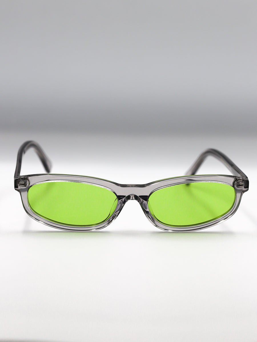 Sunglasses with green lenses and clear frames on a gradient gray background